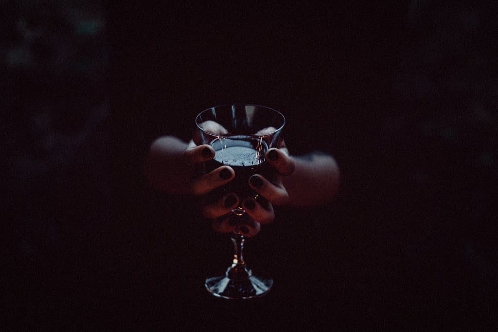 Hands holding a cocktail glass in low light