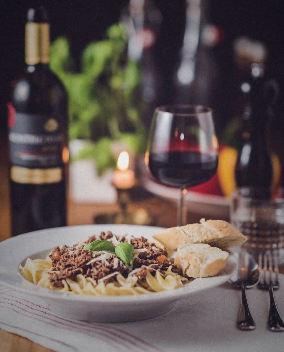 Red wine and pasta on a candlelit table